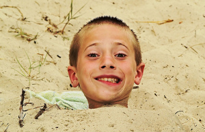 smiling boy buried in sand