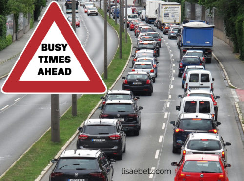 Traffic on road with "busy times ahead" sign